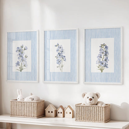 Set of three blue floral watercolor art prints in white frames, arranged above a toy organizer in a children's playroom.