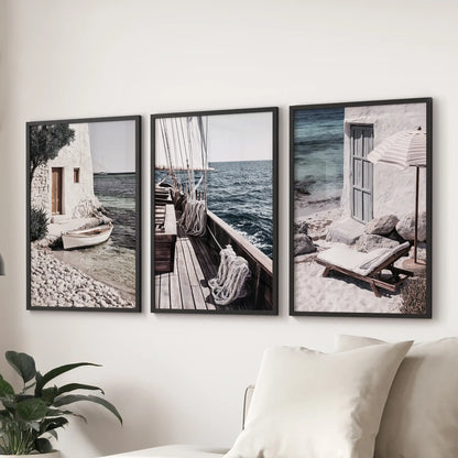 Aegean sailing scenes, a trio of wall prints in black frames, anchor the family room over the sectional sofa with relaxed coastal polish.