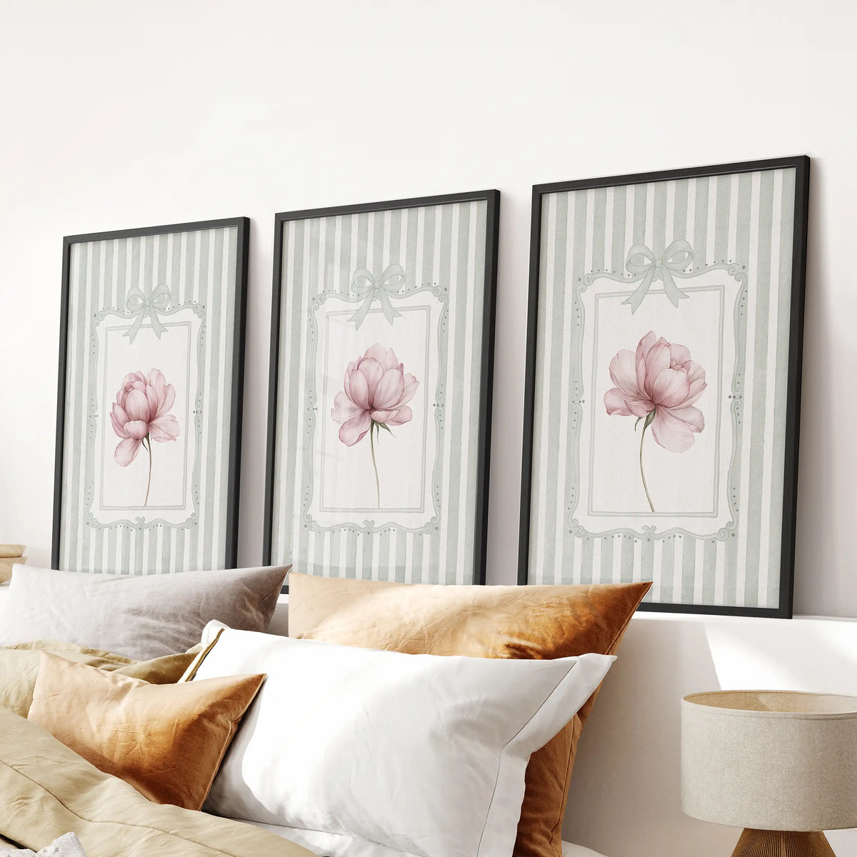Peony botanical wall art trio in black frames, displayed over a bed in a bedroom.