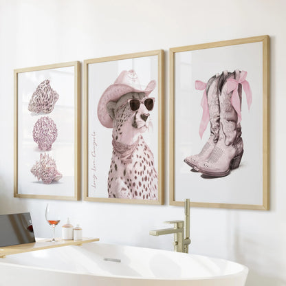 Cowgirl boots and bows three-piece wall art in thin wood frames warms a bathroom above the soaking tub with blush tones and flirty Western charm.