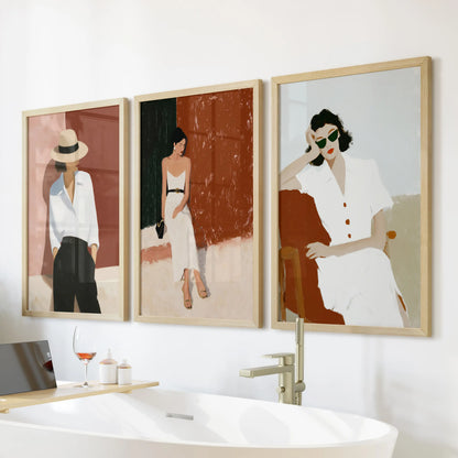 Three wooden-framed art pictures of feminine subjects float above the freestanding tub, giving the bathroom warmth and soft empowerment.