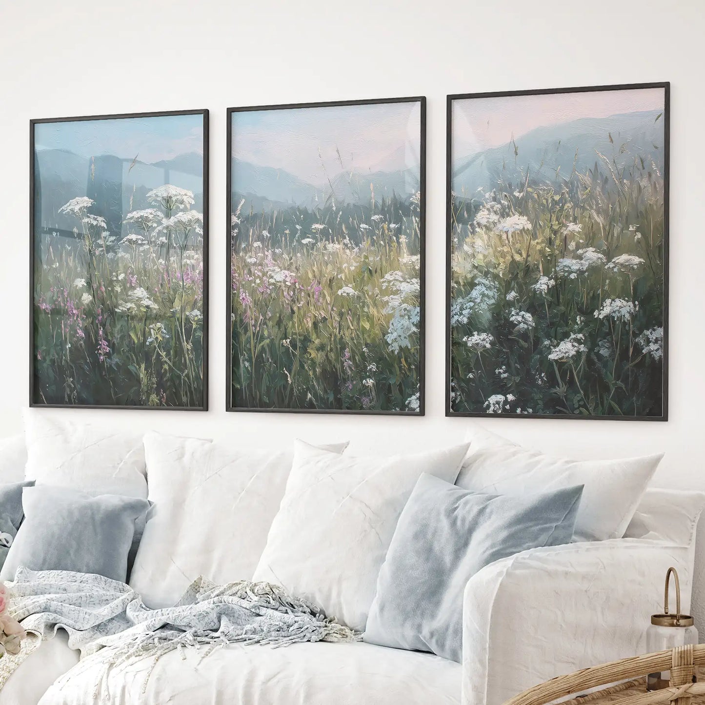 Botanical art print set with blooming field and calming blue scenery. Black frames above the sofa.
