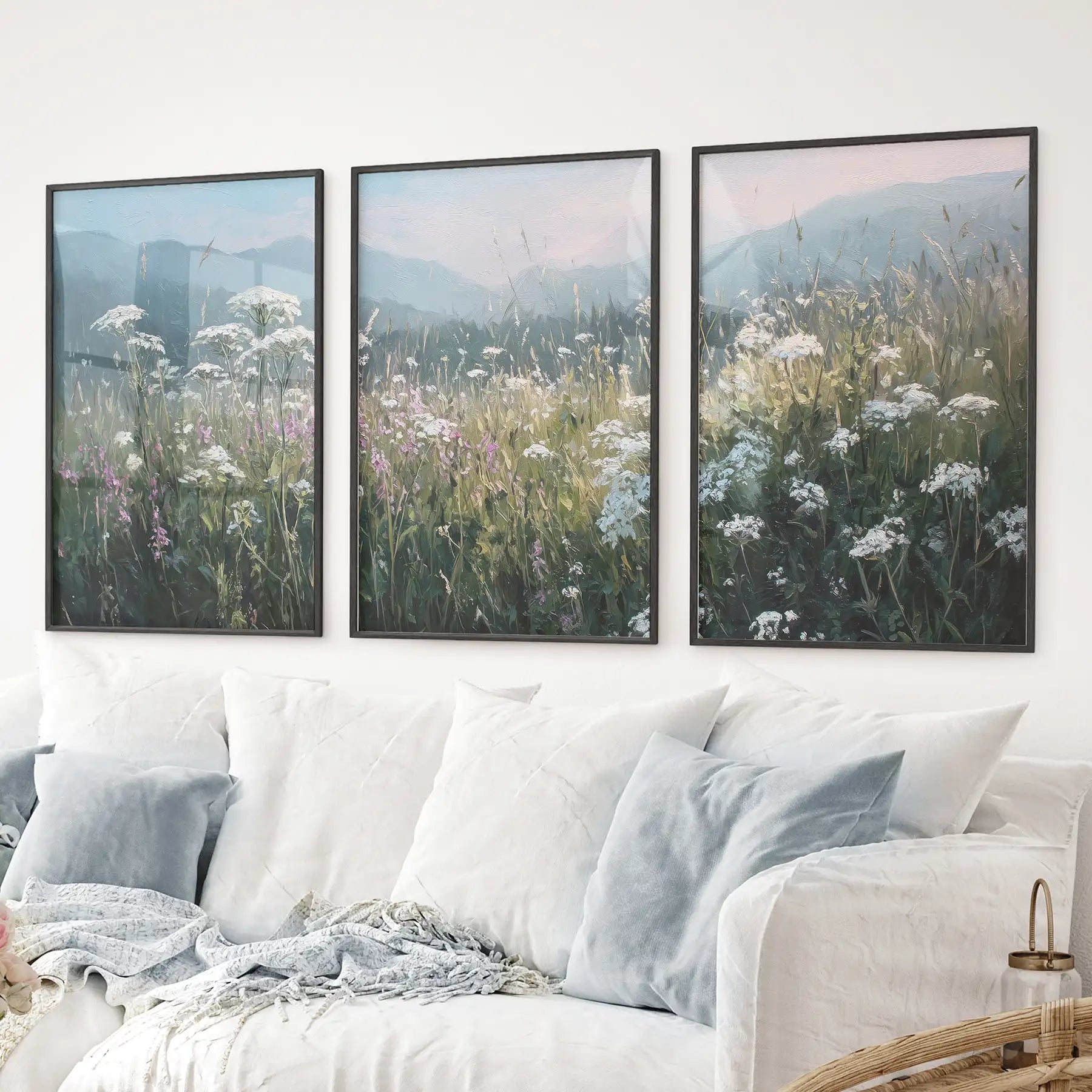 Botanical art print set with blooming field and calming blue scenery. Black frames above the sofa.