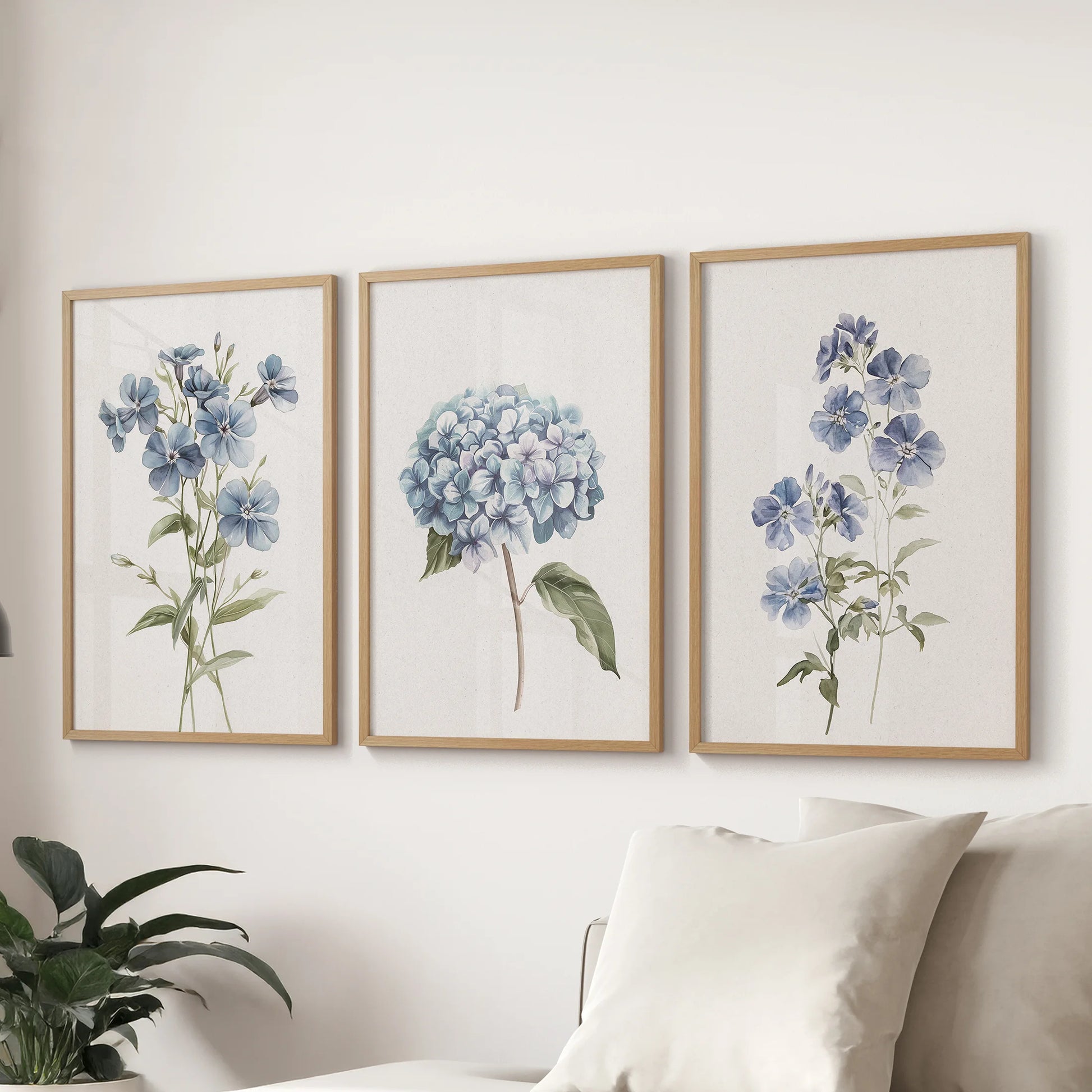 Hydrangea bouquets, three natural-wood framed pictures, span the wall above a sectional sofa to ground the living room with cool blue botanicals.