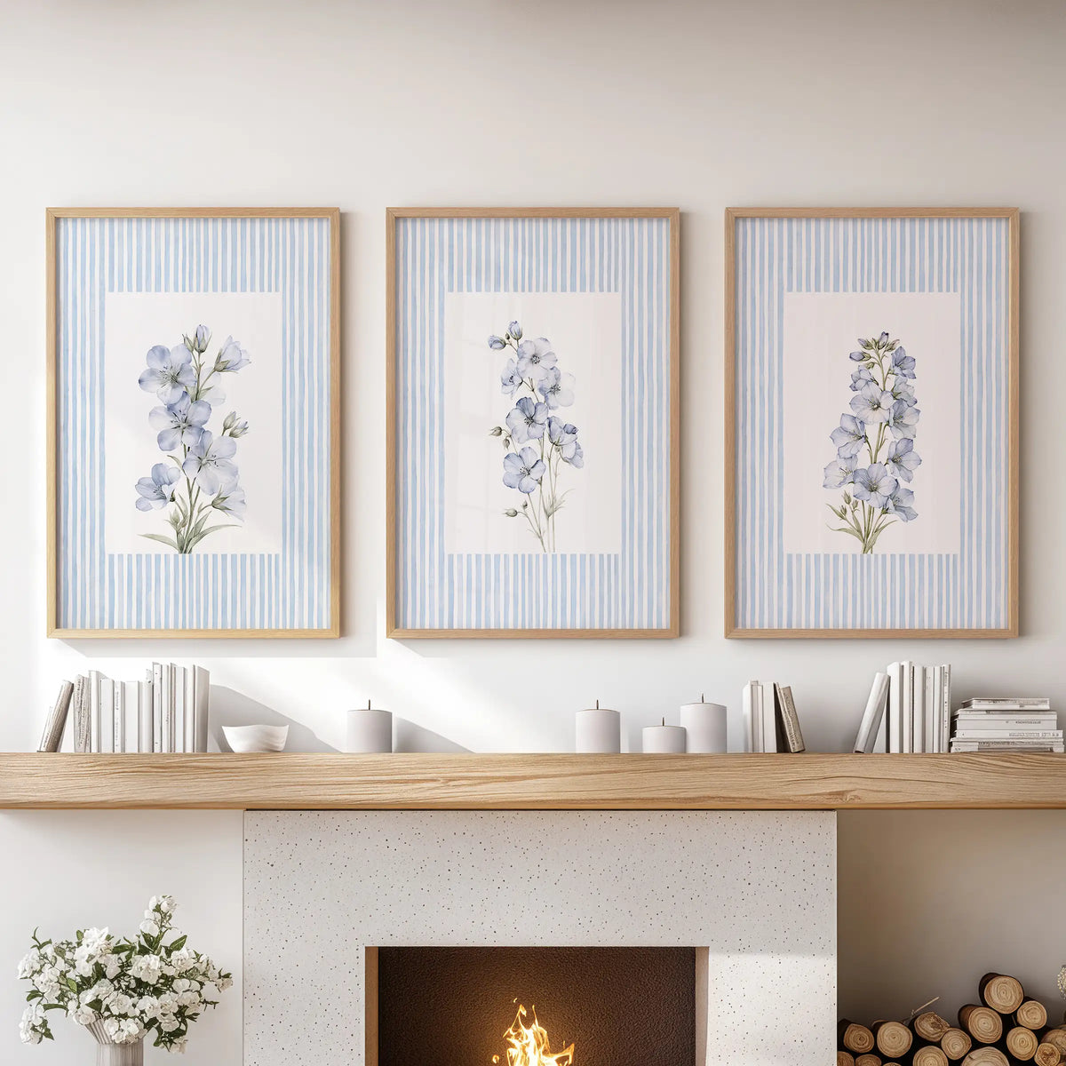 French country flowers wall art set of 3 in light oak frames, displayed over the mantel in a lounge with a blue sofa and built-in shelving.