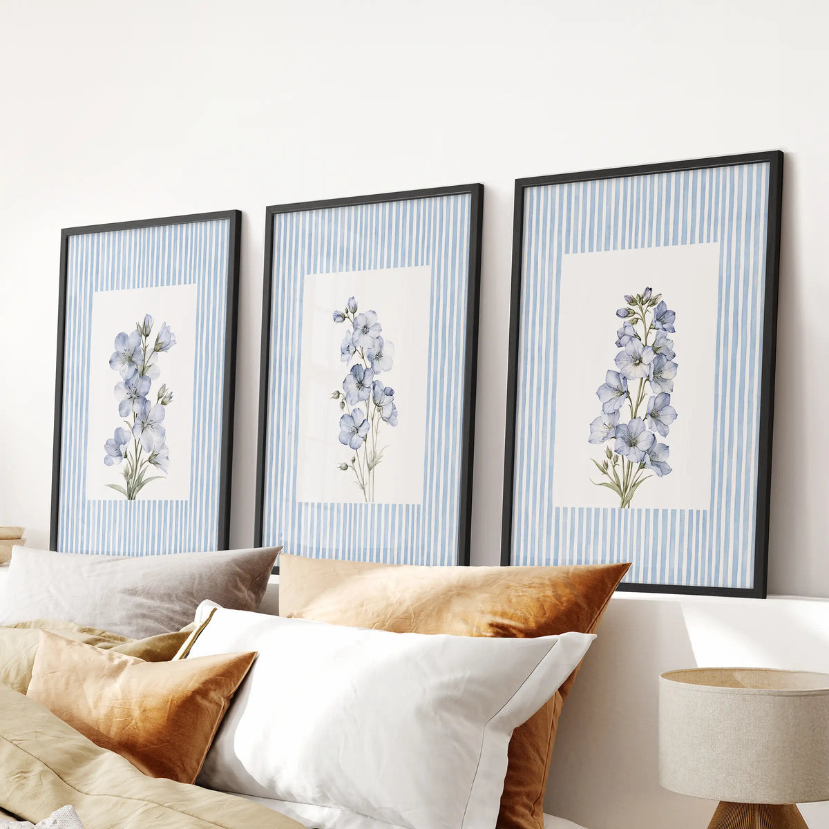 French country floral poster trio in black frames, displayed above the bed against a light blue bedroom wall.