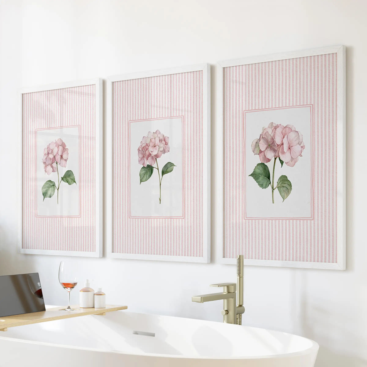 Garden flower illustrations in a 3-piece wall art print set hang in white frames above a bathtub in a bathroom.
