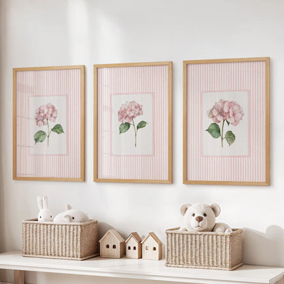 Set of three wall posters featuring garden flower illustrations in oak frames above a toy storage bench in a playroom.