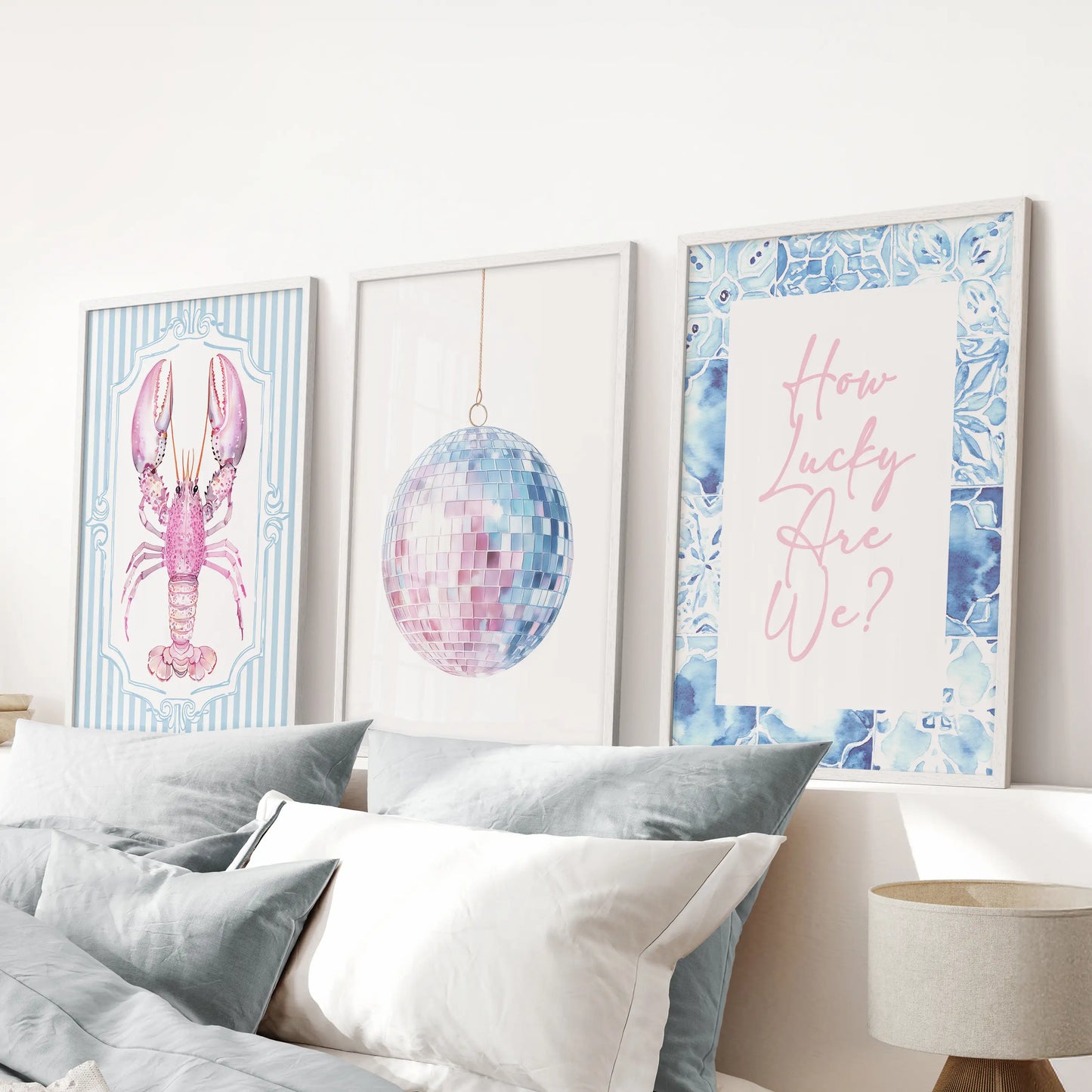 Three disco mirror ball prints in crisp white frames light up the blue bedroom above the bed, adding playful coastal shine and dorm-style fun.