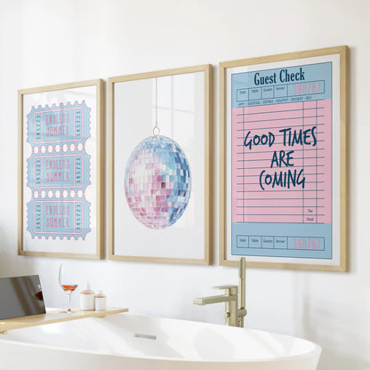 Three art prints in solid oak frames hang above the soaking tub, uniting a beach ticket, disco ball, and guest check for a sunny, feminine refresh.