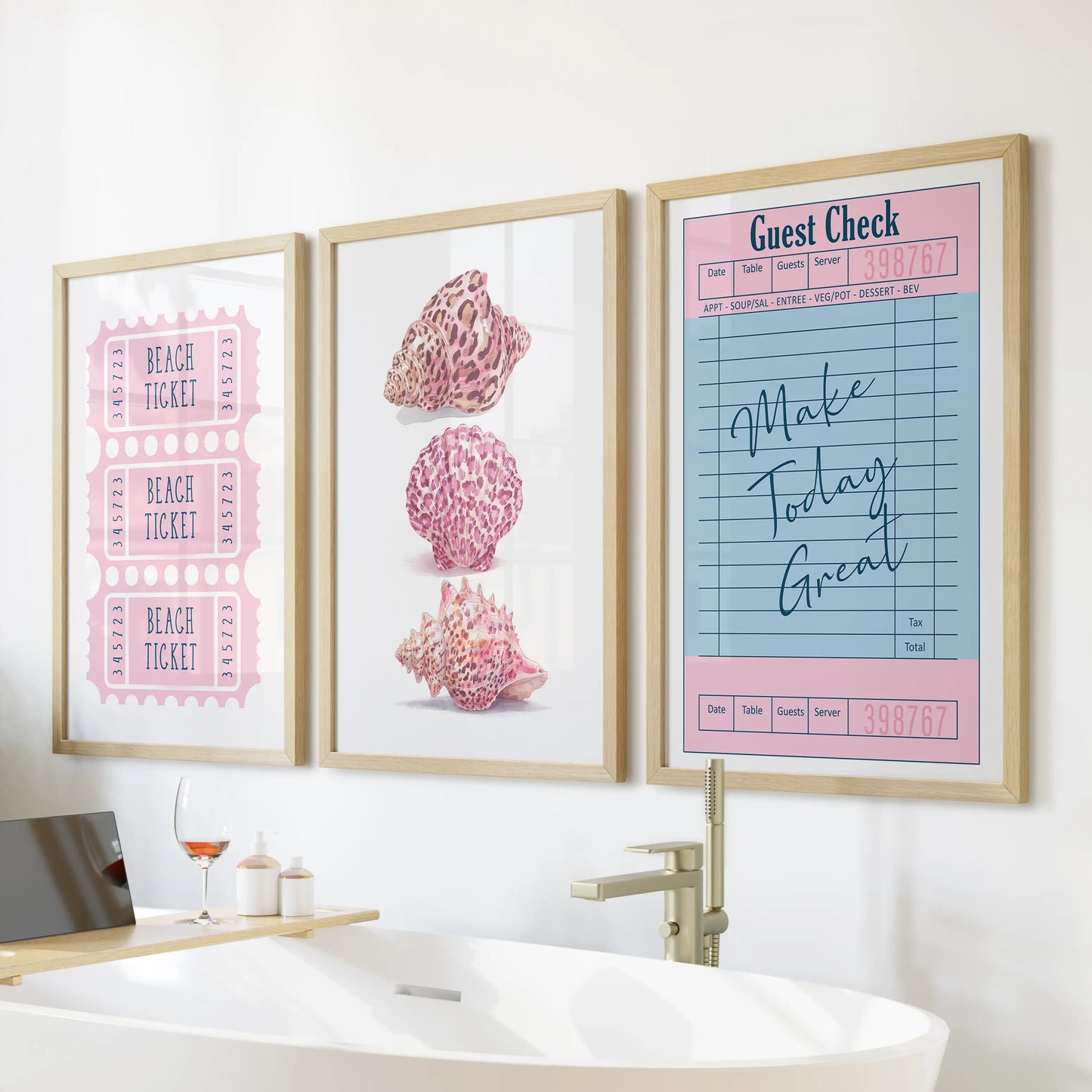 Light-oak frames hold a beach ticket print trio, arranged over a freestanding tub as playful three-piece coastal wall art.