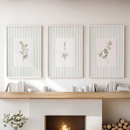 A set of three green floral botanical prints in white frames hangs over the fireplace mantel in a sitting room.