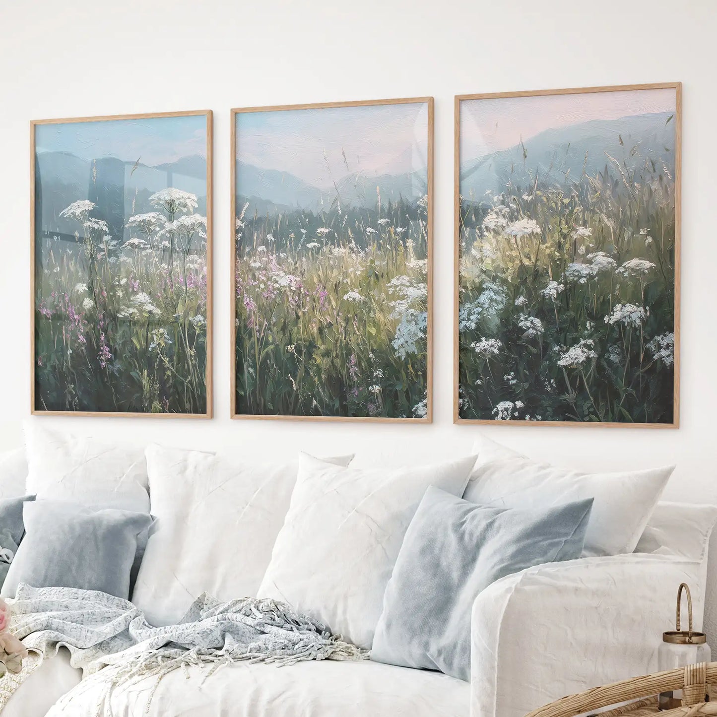 Pastel toned floral wall art with meadow flowers and hazy hills. Thinwood frames over the couch.