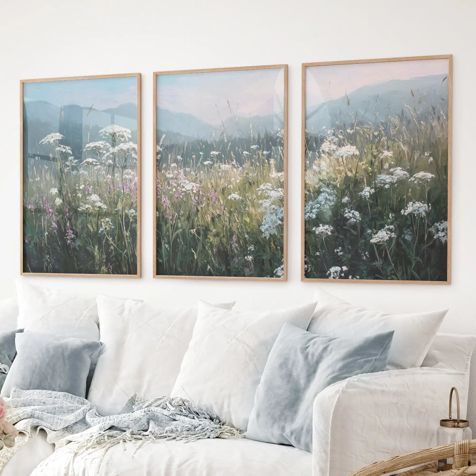 Pastel toned floral wall art with meadow flowers and hazy hills. Thinwood frames over the couch.