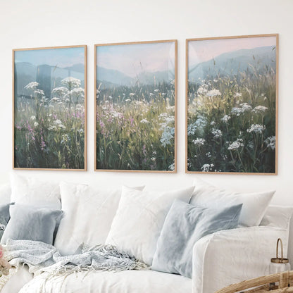 Pastel toned floral wall art with meadow flowers and hazy hills. Thinwood frames over the couch.