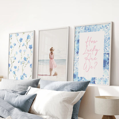 Watercolor beach scenes, a set of three framed posters, in white frames placed over the headboard in a blue bedroom to keep the palette airy and serene.