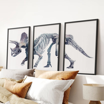 Watercolor dinosaur bones triptych wall art showing triceratops fossil design in calm grey and neutral shades.Black frames over the bed.