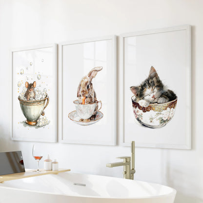A white-framed trio of wall art showing a sleepy kitty in a cup perches above the tub, watercolor tones easing the bathroom’s mood.