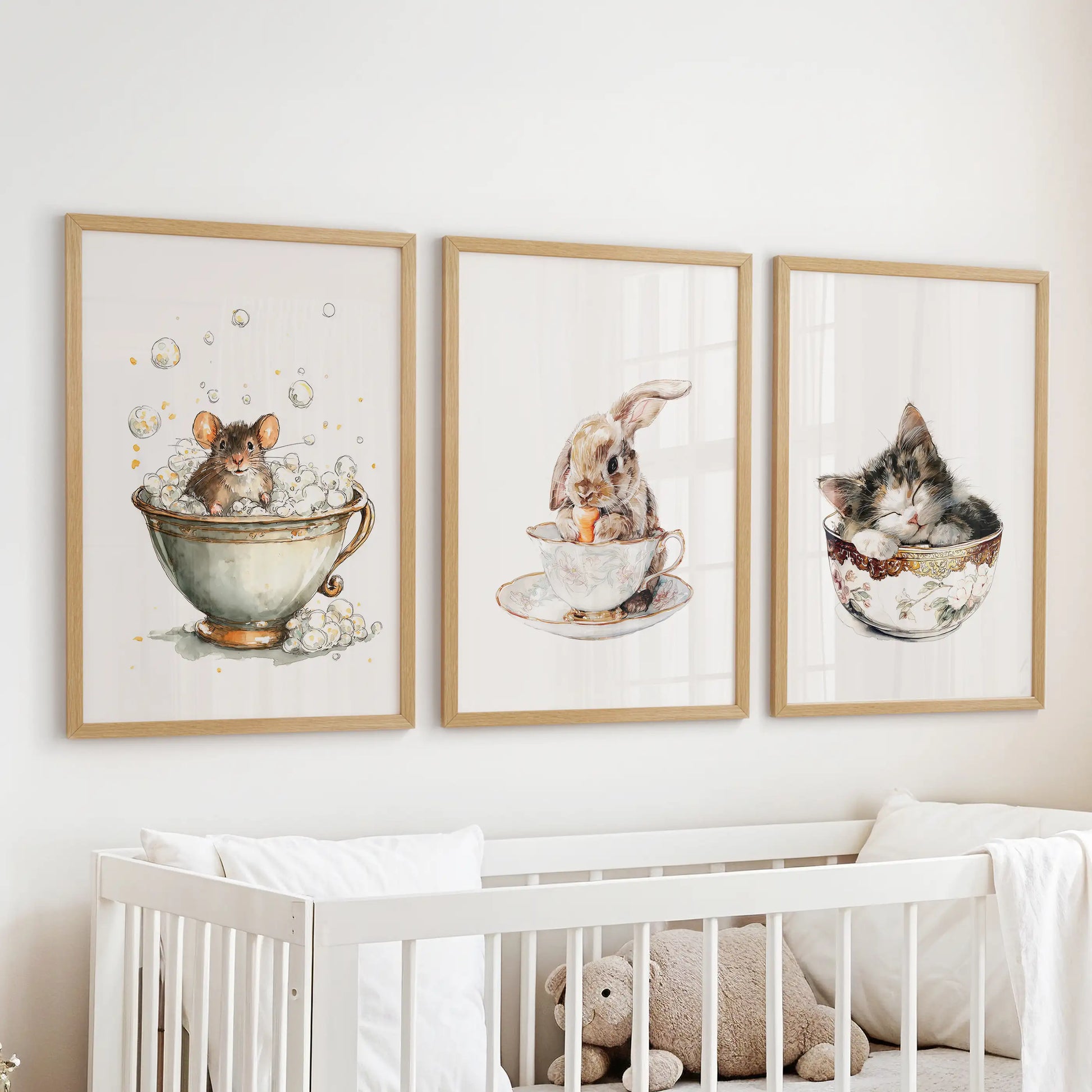 Sleepy kitty in a cup, a nursery wall art set of three in light oak frames, hangs above the bassinet with hush-soft watercolor sweetness.