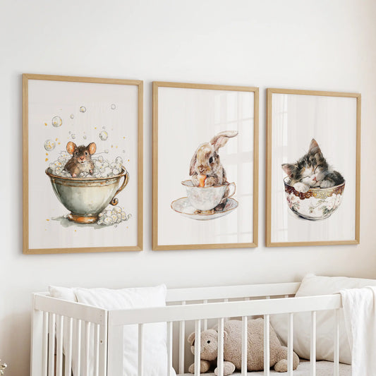 Sleepy kitty in a cup, a nursery wall art set of three in light oak frames, hangs above the bassinet with hush-soft watercolor sweetness.