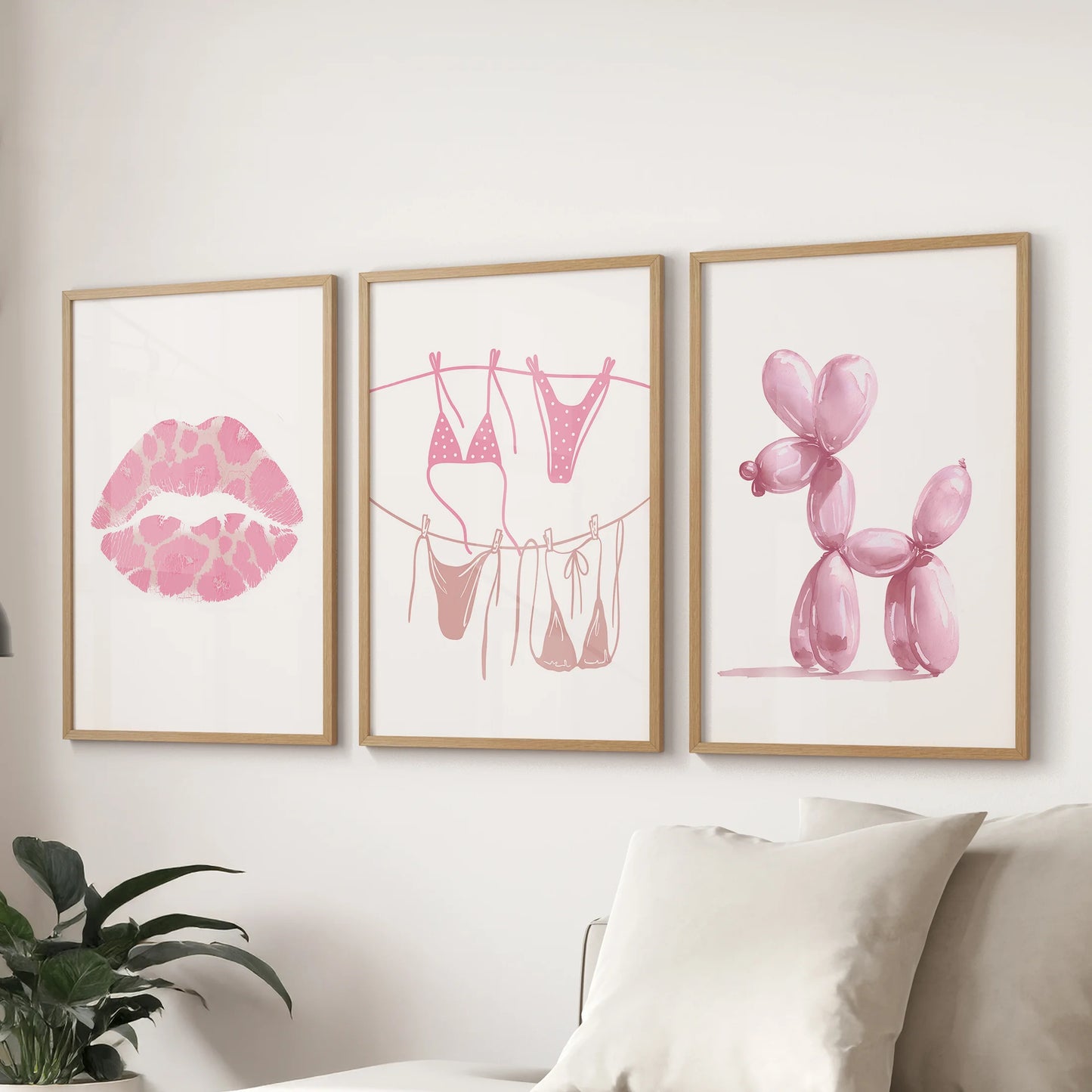 Light pink lips, bikini watercolor prints, a trio, warm the living room; wood-framed art hung over the sofa adds texture while keeping the palette soft.