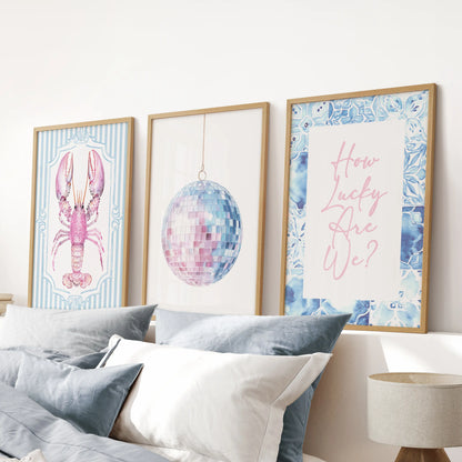 Disco mirror ball poster trio in natural oak frames hovers above the bed, lending the blue bedroom a glossy beach-club sparkle in soft pastels.