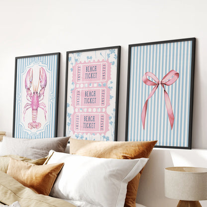 A set of three lobster illustrations in sleek black frames grounds the wall above a blue bed, giving the bedroom a crisp coastal feel.