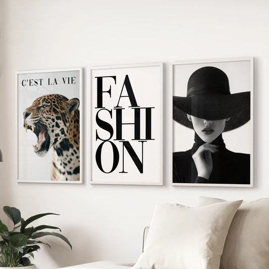 A three-piece fashion artwork in white frames hangs behind the couch, lending the sitting room a crisp, luxurious feel.