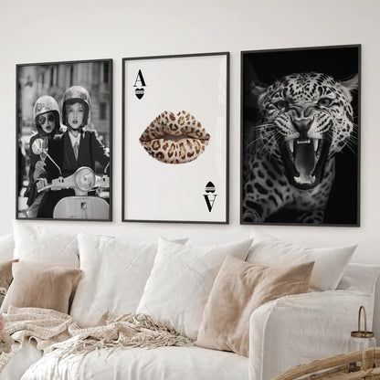 Glam wall art triptych with leopard, lips playing card, and stylish scooter poster. Black frames over the couch.