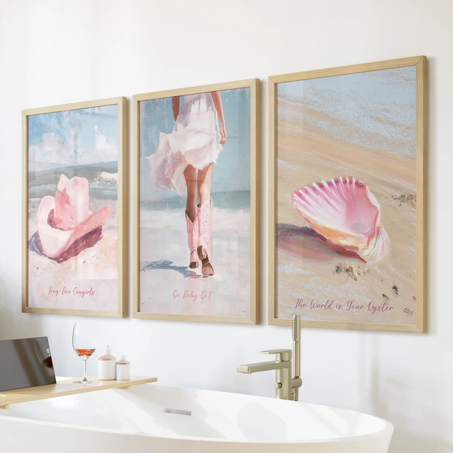 Coastal cowgirl aesthetic 3-print wall art bundle in warm wood frames hangs above a freestanding tub, balancing beach light with a playful western twist.