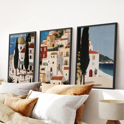 Three Spanish seaside village prints in black frames hang neatly above the bed, centering a bedroom with an easy coastal feel.