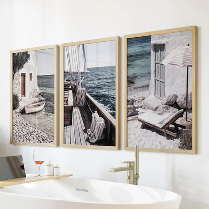 Aegean sailing scenes wall art in three pieces with oak frames, mounted above the bathtub wall for warm, natural coastal texture in the bath.