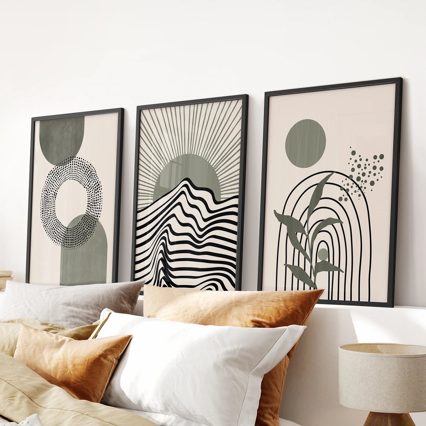 A trio of boho neutral wall art with soft sage leaves sits above the bedroom headboard, framed in slim black for a clean mid-century feel.