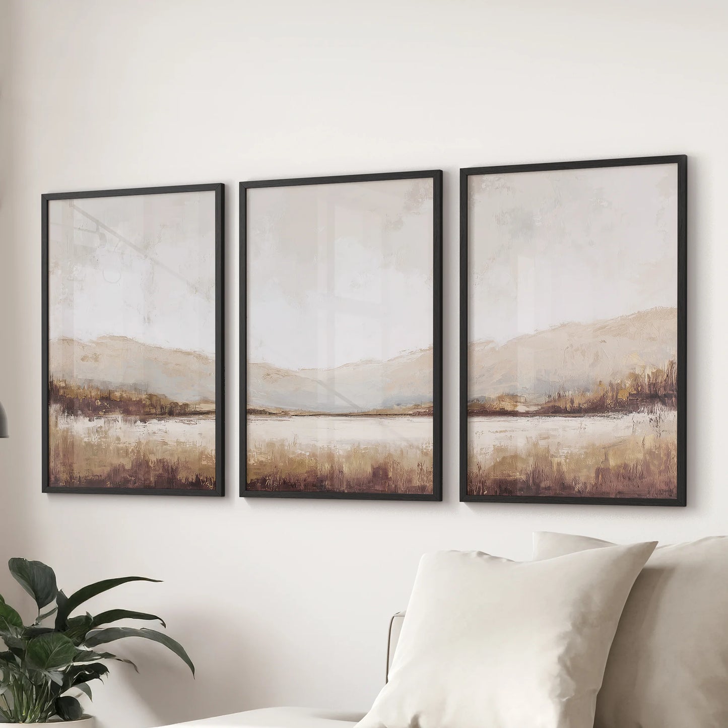 Three abstract landscape art prints in black frames line the wall above a sectional, giving the sitting room balanced neutral tone.
