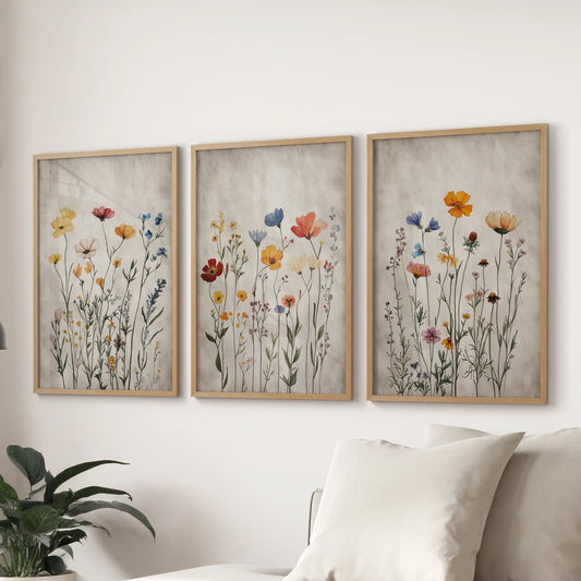 This three-piece art set in solid oak frames displays soft boho florals, arranged across the sitting room wall above a sectional sofa for warmth.