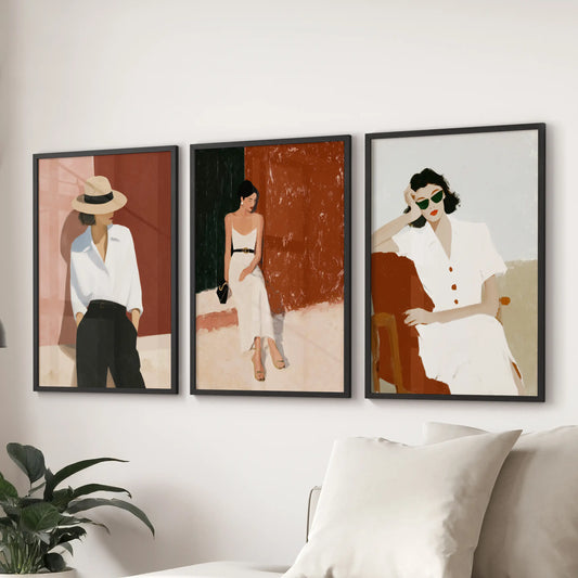 Feminine fine art paintings, a three-print wall set, line the space behind the couch in the sitting room, finished in crisp black framed styling.