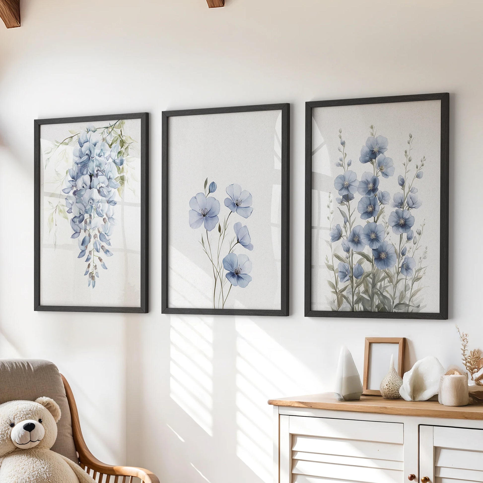 Blue watercolor florals, a set of three wall art prints, sit in black frames above the children's chest of drawers to bring calm, airy color to the room.
