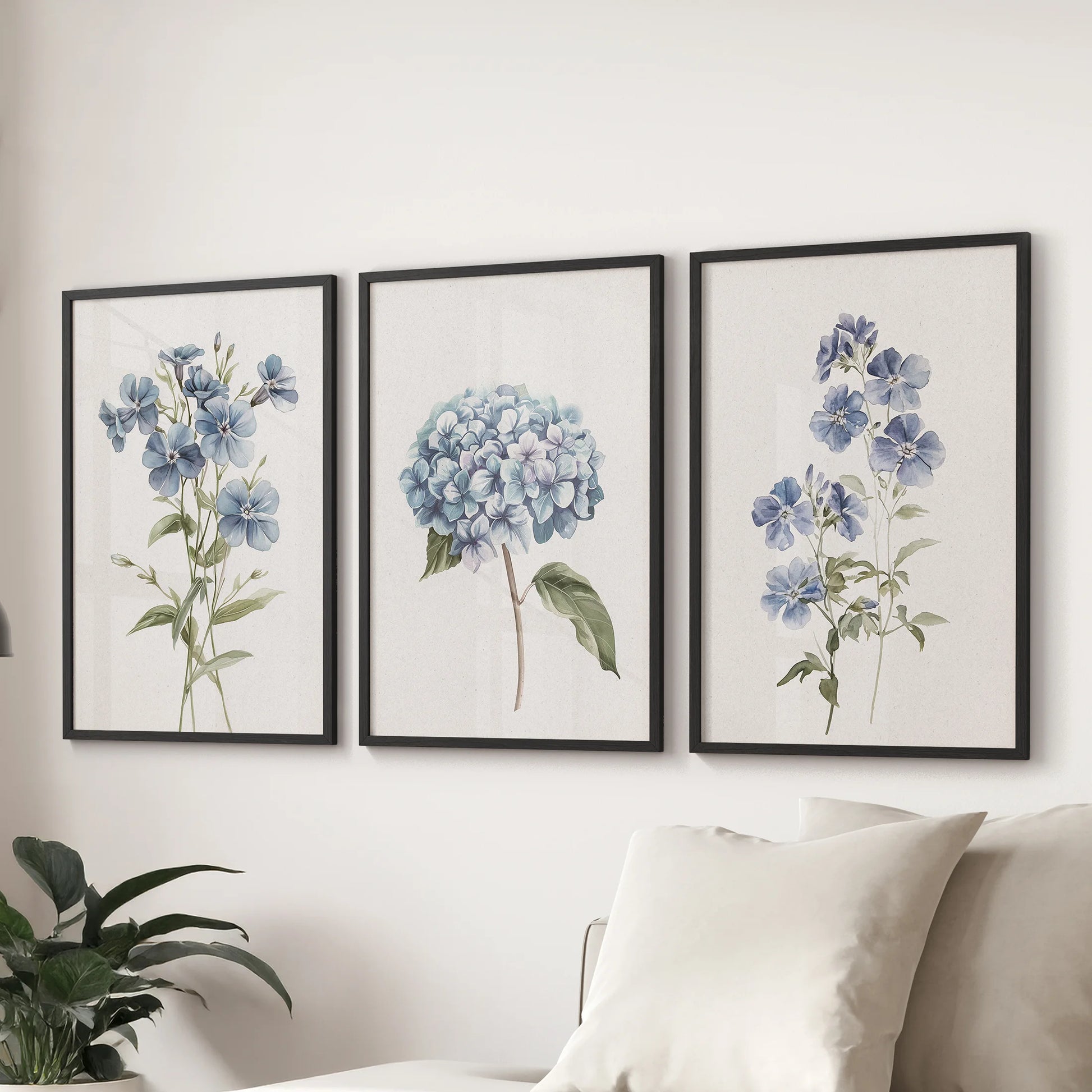 Delicate blue petals, a 3-piece art print set in black frames, anchor the living room over the sofa with calm, modern botanical wall art.