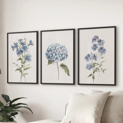 Delicate blue petals, a 3-piece art print set in black frames, anchor the living room over the sofa with calm, modern botanical wall art.