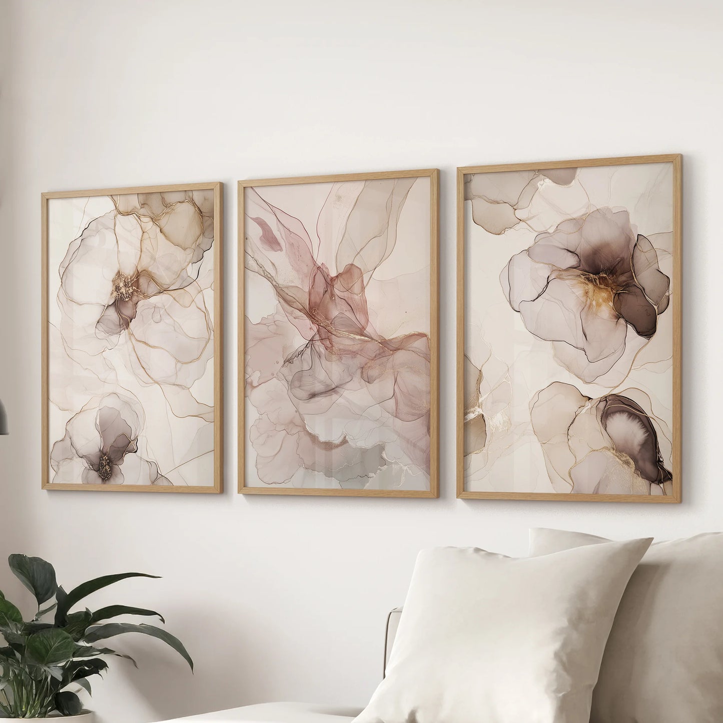 A set of three artwork prints in natural wood frames shows blush and beige abstractions, giving the lounge a gentle modern look over the couch.