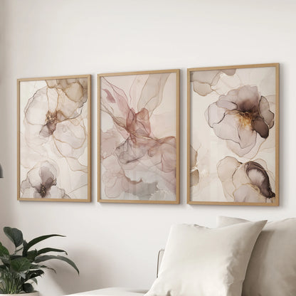 A set of three artwork prints in natural wood frames shows blush and beige abstractions, giving the lounge a gentle modern look over the couch.