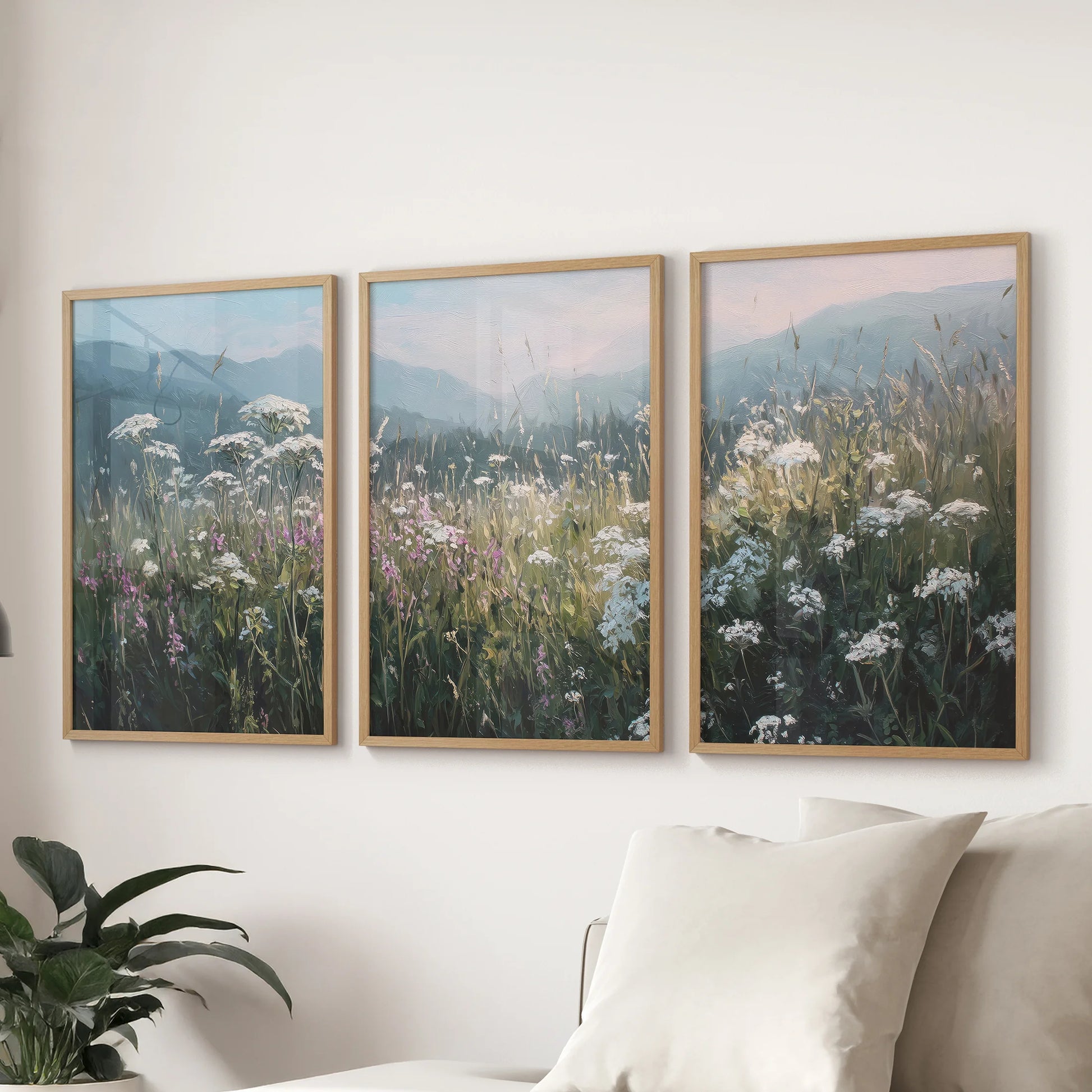 Muted landscape wall art in three natural wood-framed panels rests above the sectional, offering a soft vintage calm to the sitting room.