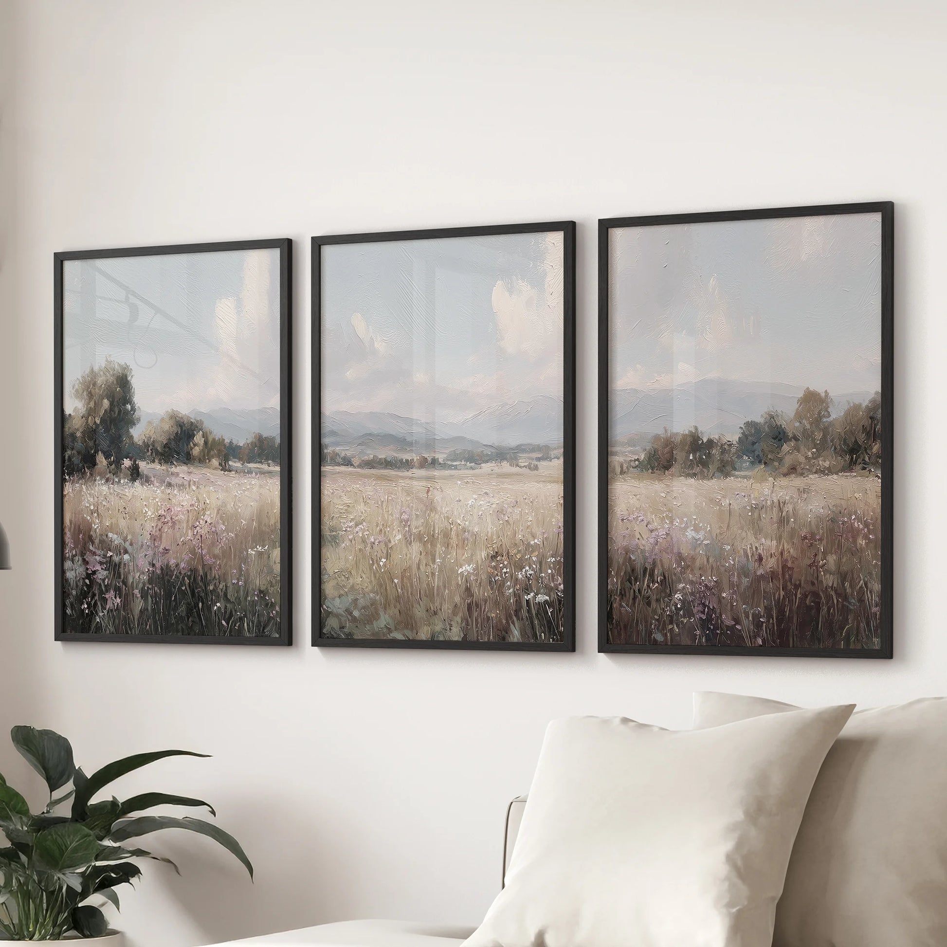 Rustic farmhouse landscape art print trio brings a neutral country mood to the sitting room, mounted in black frames behind the couch.