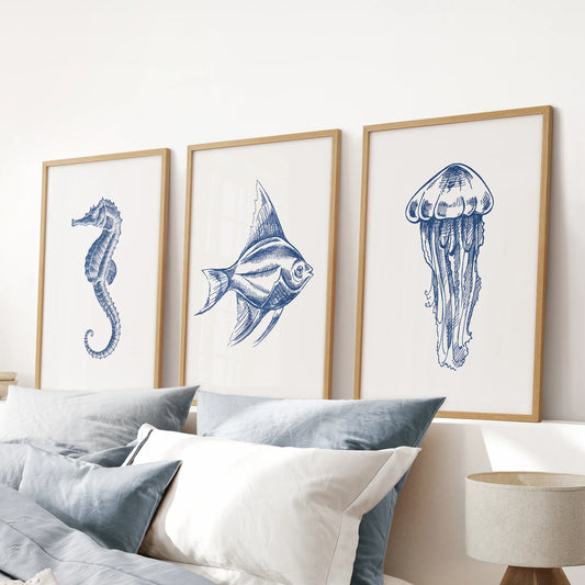 Wood-framed 3-piece fish wall art anchors the blue bedroom above the headboard, merging beach-house ease with clean modern lines.