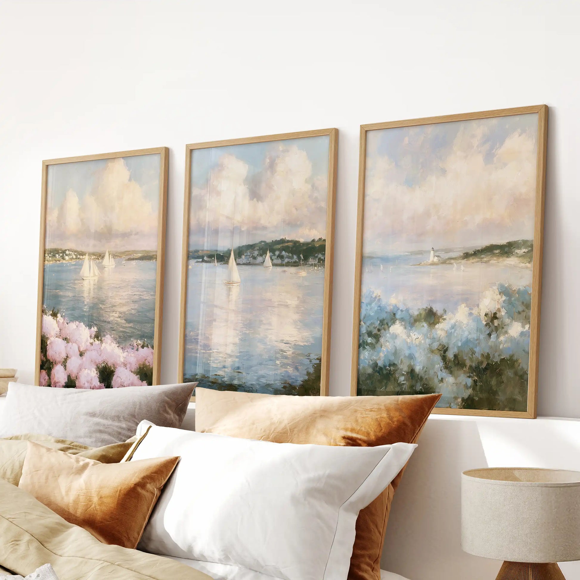 A three-piece wall decor set of Nantucket sailboats hangs above the bedroom bed. Warm wood frames surround a calm triptych of masts, hulls, and open harbor air.
