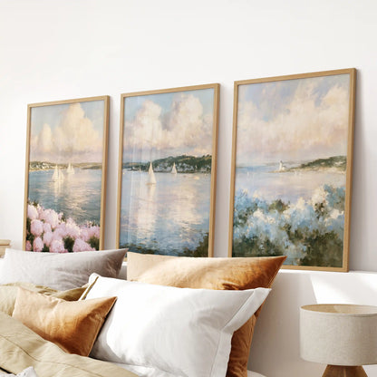 A three-piece wall decor set of Nantucket sailboats hangs above the bedroom bed. Warm wood frames surround a calm triptych of masts, hulls, and open harbor air.