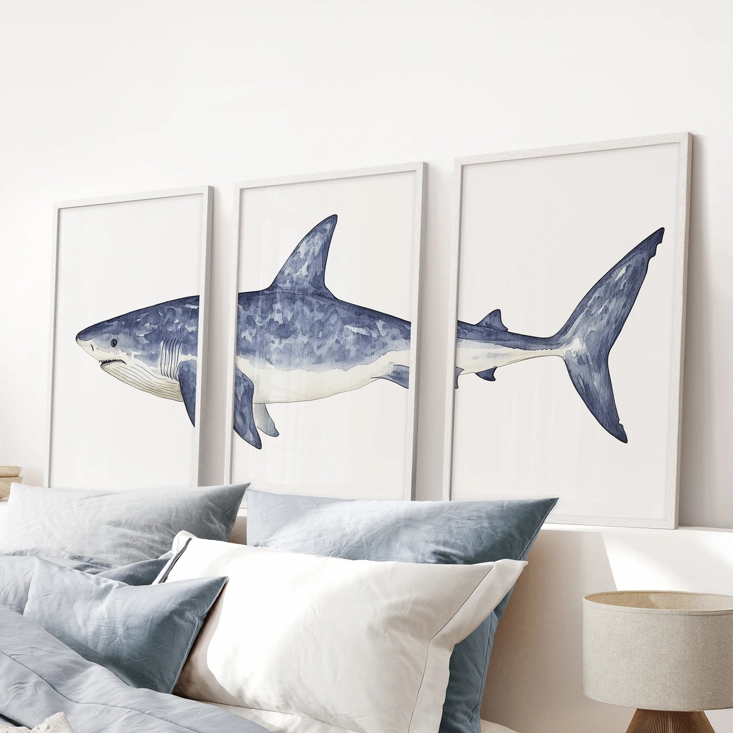 Navy blue coastal sharks, set of 3 prints, come as white framed pieces for a pink bedroom, adding a crisp nautical accent over the bed.