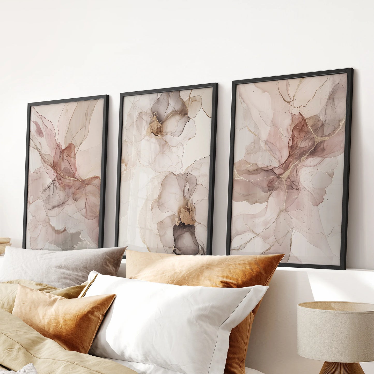 Three black-framed blush pink abstract floral prints form a 3-piece wall art set that adds a soft, modern touch above a bedroom headboard.