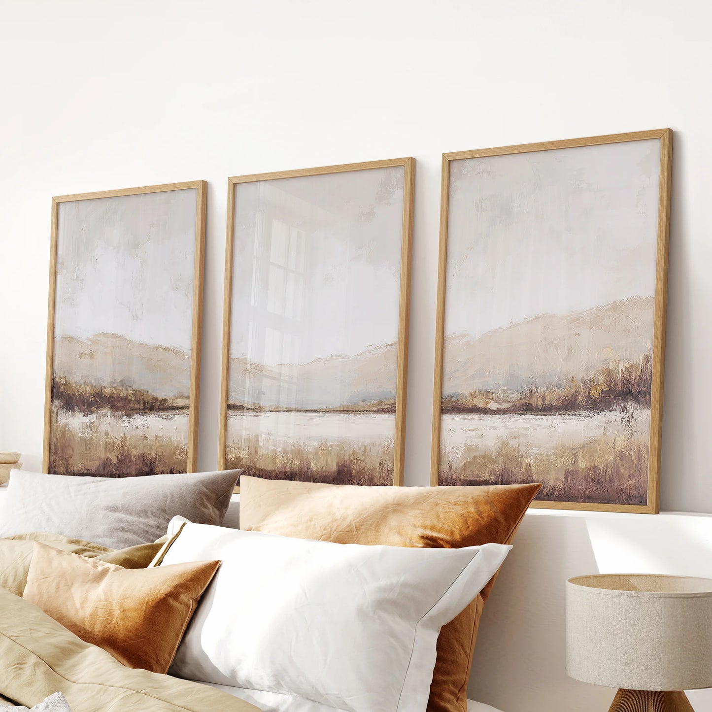 Three-piece neutral landscape wall art in warm wood frames decorates the bedroom above the headboard, lending an earthy farmhouse touch.