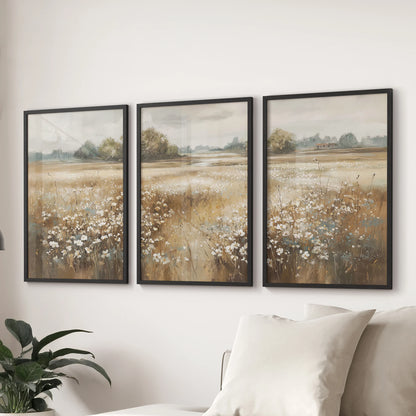 Countryside landscape art prints, a 3-print set with slim black frames, anchor the living room wall over the couch with muted, vintage farmhouse charm.